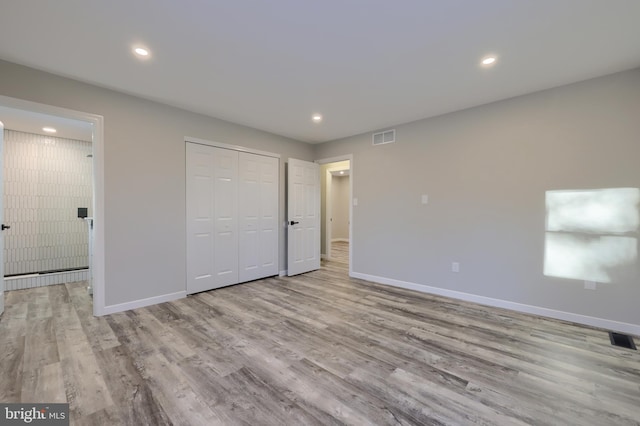 unfurnished bedroom with light wood-type flooring and a closet