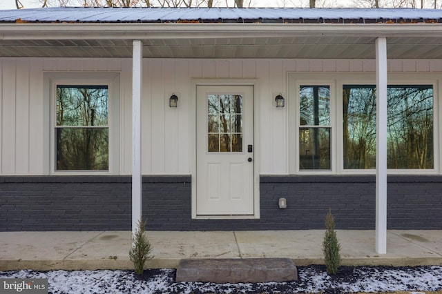 snow covered property entrance featuring a porch