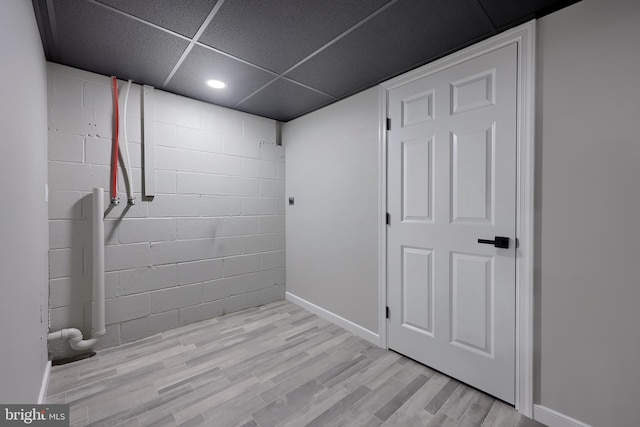 basement featuring a paneled ceiling and light hardwood / wood-style floors