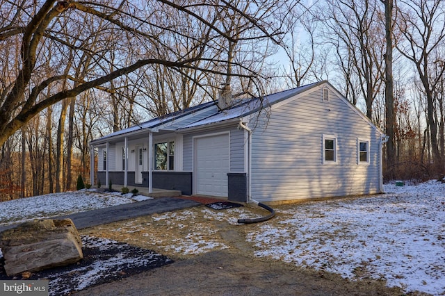 view of snow covered exterior featuring covered porch and a garage