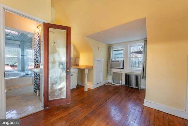 additional living space with dark hardwood / wood-style flooring, radiator, and cooling unit