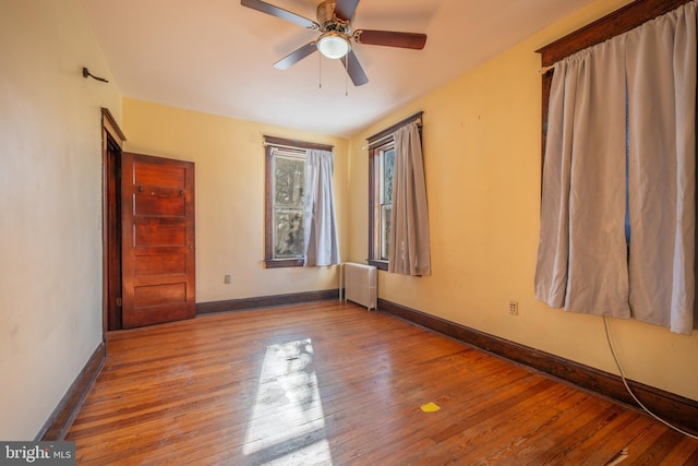 unfurnished room featuring ceiling fan, radiator, and hardwood / wood-style floors