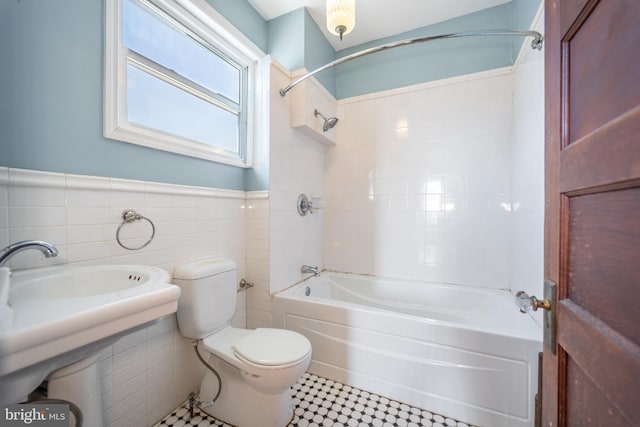 bathroom featuring tiled shower / bath combo, tile walls, and toilet