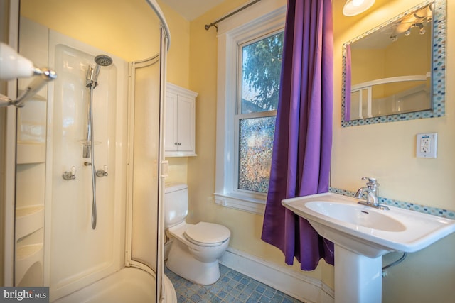 bathroom featuring a shower with door and toilet