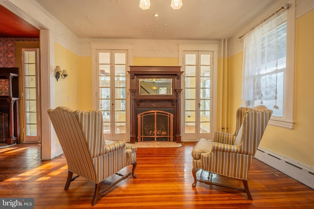 living area featuring a baseboard heating unit and hardwood / wood-style floors