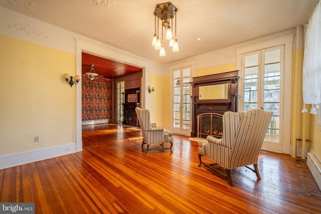 sitting room with baseboard heating, wood-type flooring, and a chandelier