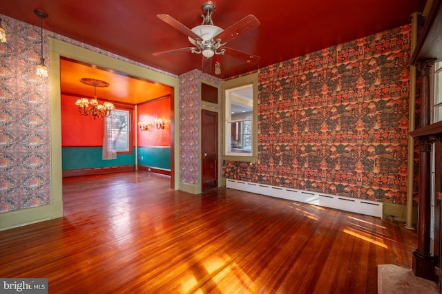 spare room with ceiling fan with notable chandelier, a baseboard heating unit, and hardwood / wood-style floors