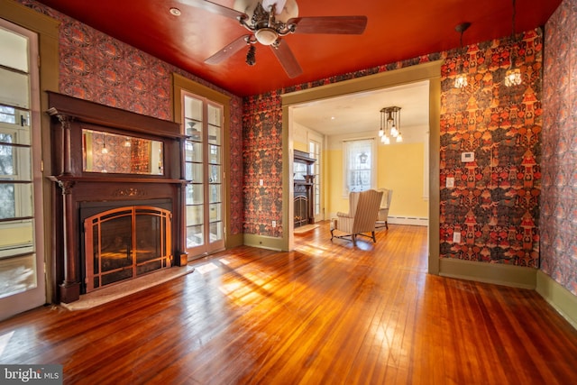 unfurnished living room with hardwood / wood-style flooring, a baseboard radiator, and ceiling fan