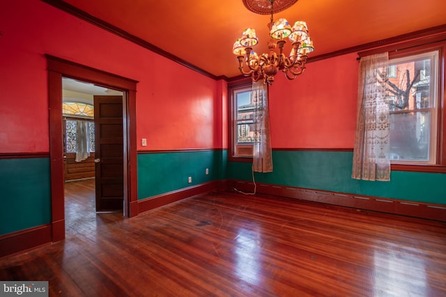 unfurnished room with hardwood / wood-style flooring, ornamental molding, and a chandelier