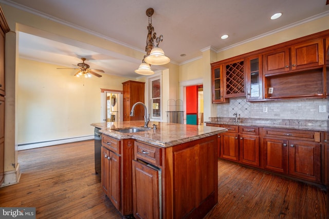 kitchen with an island with sink, sink, backsplash, hanging light fixtures, and a baseboard heating unit