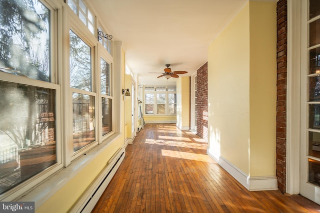 hall featuring wood-type flooring, brick wall, and a baseboard heating unit