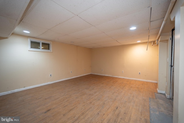 basement featuring a paneled ceiling and hardwood / wood-style floors