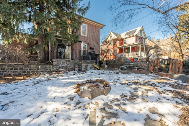 snow covered back of property with an outdoor fire pit