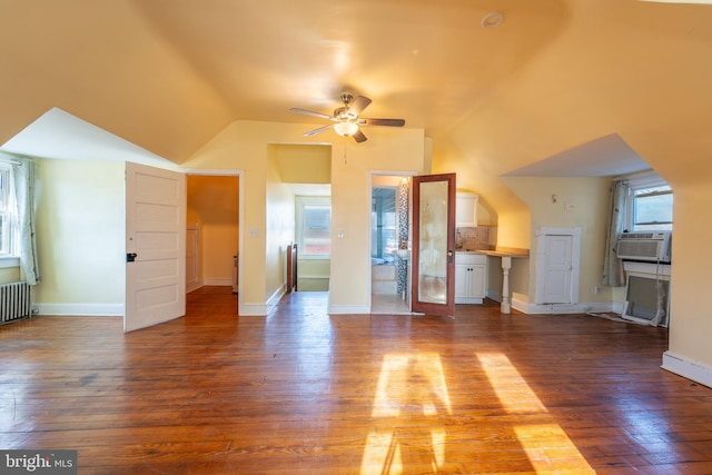 unfurnished living room with vaulted ceiling, radiator, cooling unit, hardwood / wood-style flooring, and ceiling fan