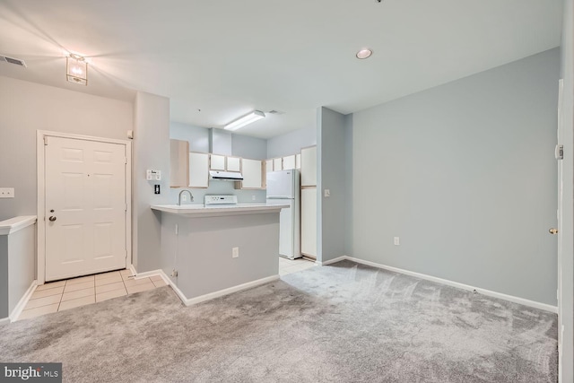 kitchen with white appliances, light carpet, white cabinets, sink, and kitchen peninsula