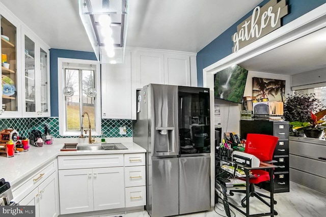 kitchen featuring stainless steel fridge, white cabinetry, sink, and tasteful backsplash