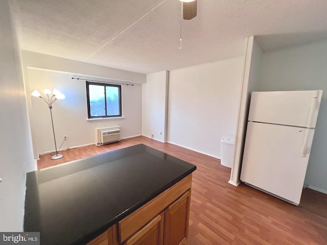 kitchen with a textured ceiling, white fridge, light hardwood / wood-style flooring, and a wall mounted AC