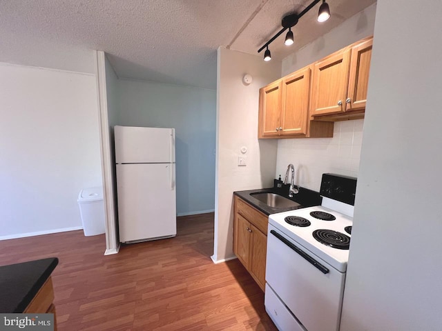 kitchen with light brown cabinets, white appliances, sink, hardwood / wood-style flooring, and a textured ceiling