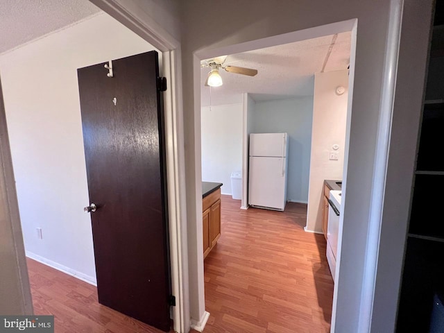 hall with a textured ceiling and light hardwood / wood-style floors