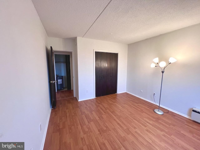 unfurnished bedroom with a closet, wood-type flooring, and a textured ceiling