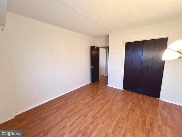 unfurnished bedroom with a textured ceiling, light hardwood / wood-style flooring, and a closet