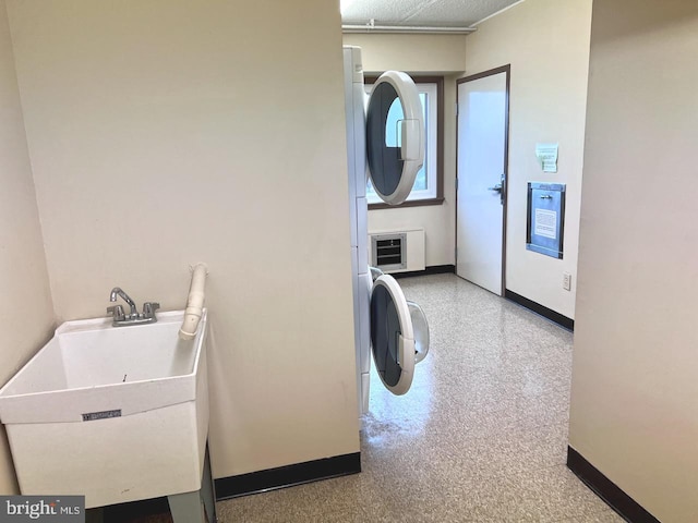 laundry area with heating unit, sink, and stacked washing maching and dryer