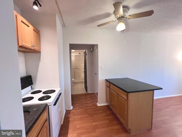 kitchen with a textured ceiling, light hardwood / wood-style floors, ceiling fan, and electric stove