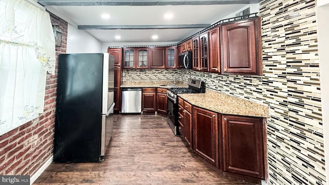 kitchen featuring light stone countertops, appliances with stainless steel finishes, backsplash, and dark hardwood / wood-style floors