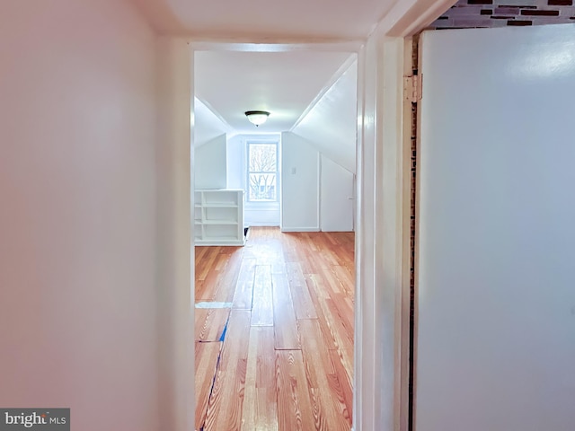 hallway with light hardwood / wood-style flooring and vaulted ceiling