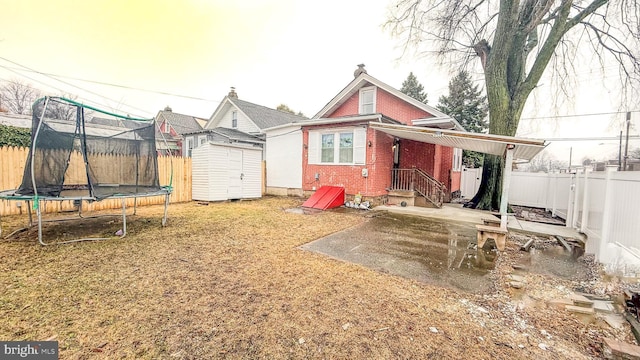 rear view of property featuring a trampoline and a shed