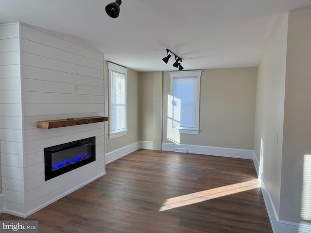 unfurnished living room with track lighting, dark hardwood / wood-style flooring, and a fireplace