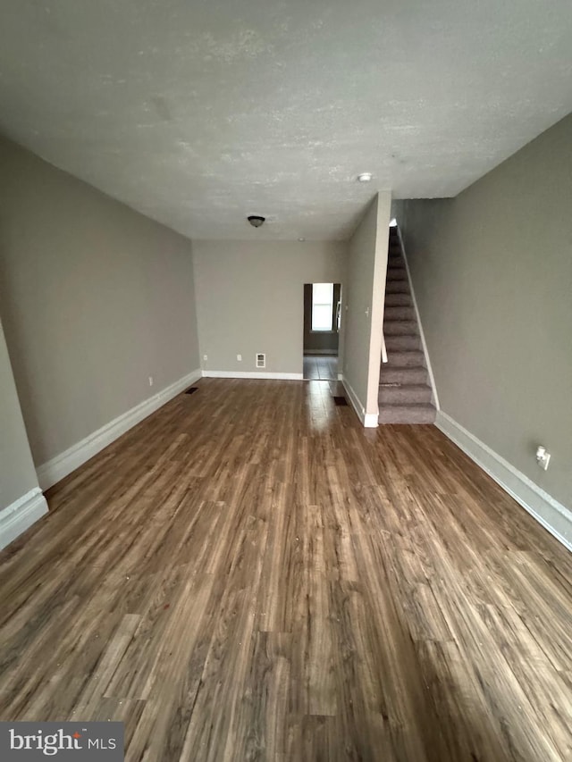 unfurnished living room featuring a textured ceiling and dark wood-type flooring