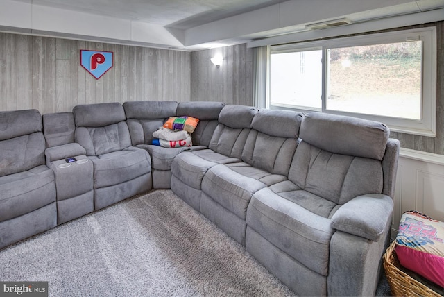 carpeted living room featuring wood walls