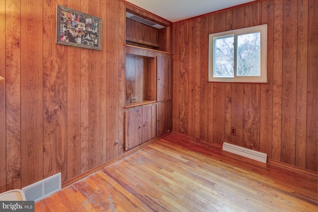 unfurnished room with wooden walls and light hardwood / wood-style flooring