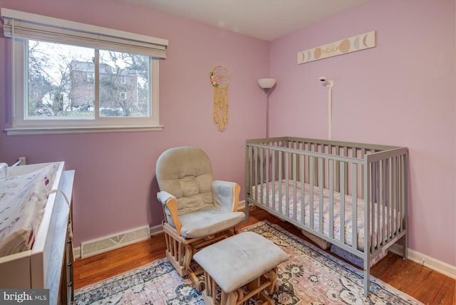 bedroom with light hardwood / wood-style floors and a crib