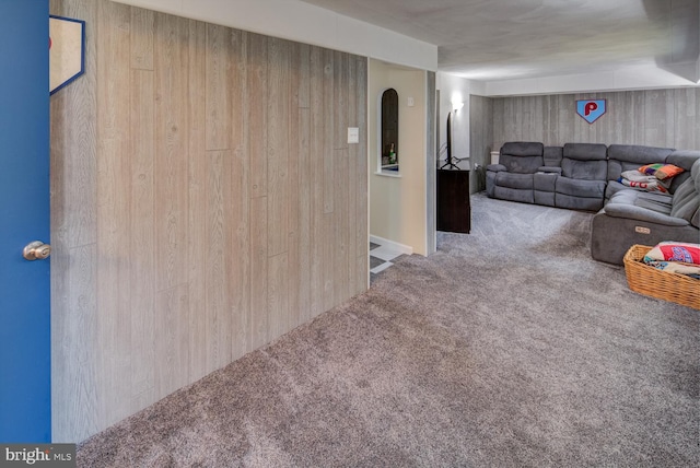 unfurnished living room featuring carpet flooring and wood walls