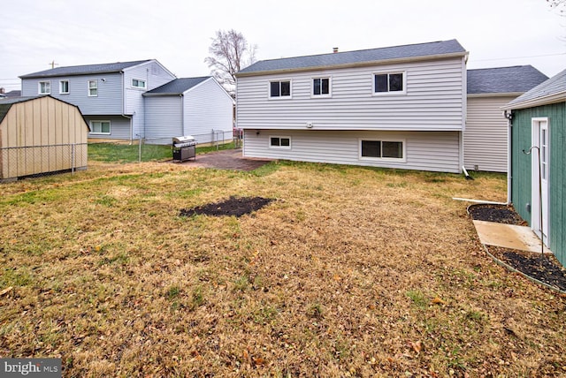 rear view of property featuring a lawn and a storage unit