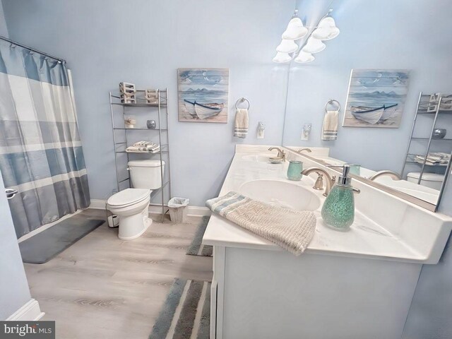 bathroom with vanity, wood-type flooring, a shower with curtain, toilet, and a chandelier