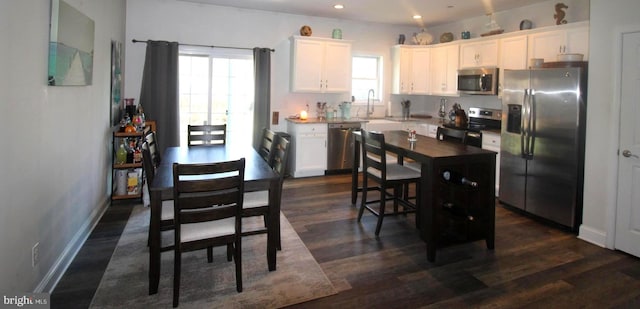 kitchen with a kitchen island, white cabinetry, sink, stainless steel appliances, and dark wood-type flooring