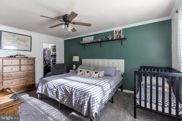 carpeted bedroom featuring a closet, ceiling fan, crown molding, and a spacious closet