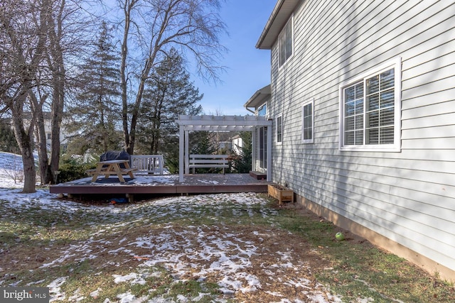 yard layered in snow with a pergola and a deck