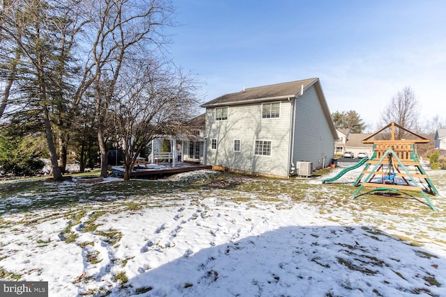 snow covered property with a playground and central AC