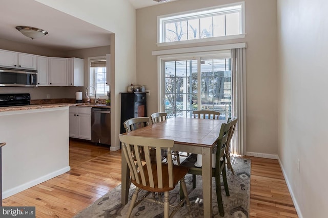 dining space featuring plenty of natural light, sink, and light hardwood / wood-style flooring