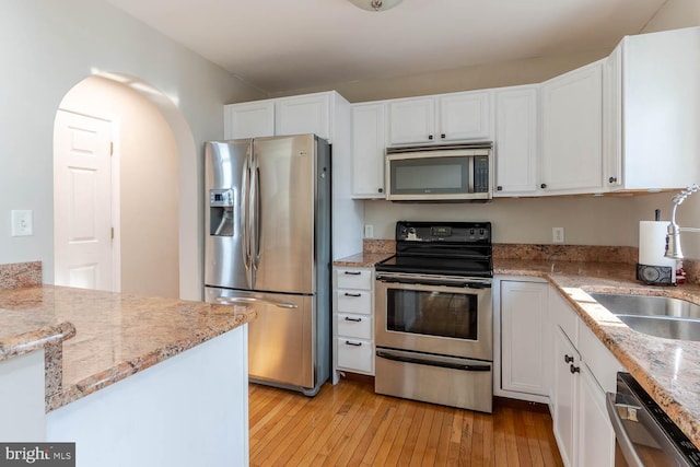 kitchen with white cabinetry, sink, light hardwood / wood-style floors, and appliances with stainless steel finishes