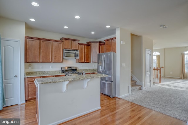 kitchen featuring a kitchen bar, appliances with stainless steel finishes, light hardwood / wood-style floors, and a kitchen island