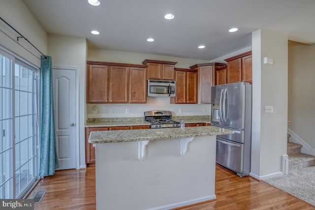 kitchen featuring a kitchen bar, light hardwood / wood-style flooring, a kitchen island, and appliances with stainless steel finishes