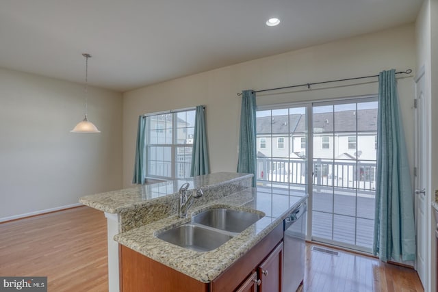 kitchen featuring a kitchen island with sink, sink, light hardwood / wood-style floors, and decorative light fixtures