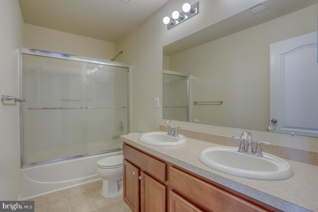 full bathroom featuring combined bath / shower with glass door, vanity, tile patterned flooring, and toilet