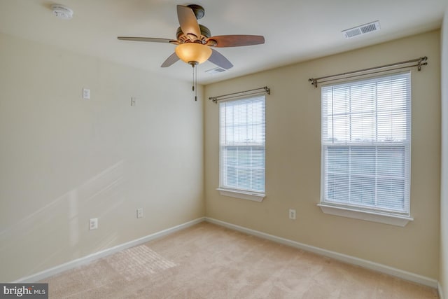 unfurnished room with a wealth of natural light, ceiling fan, and light carpet