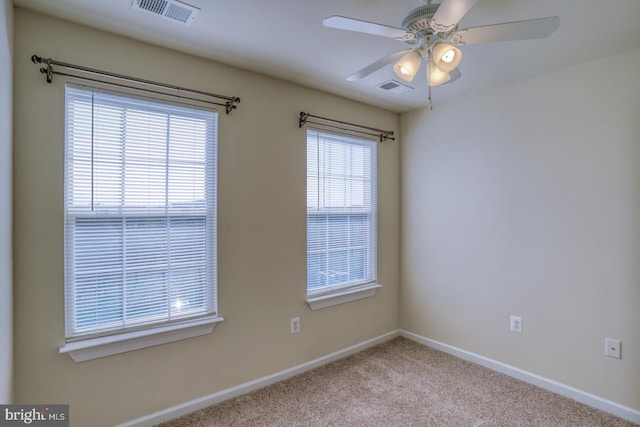 carpeted empty room featuring ceiling fan and a wealth of natural light